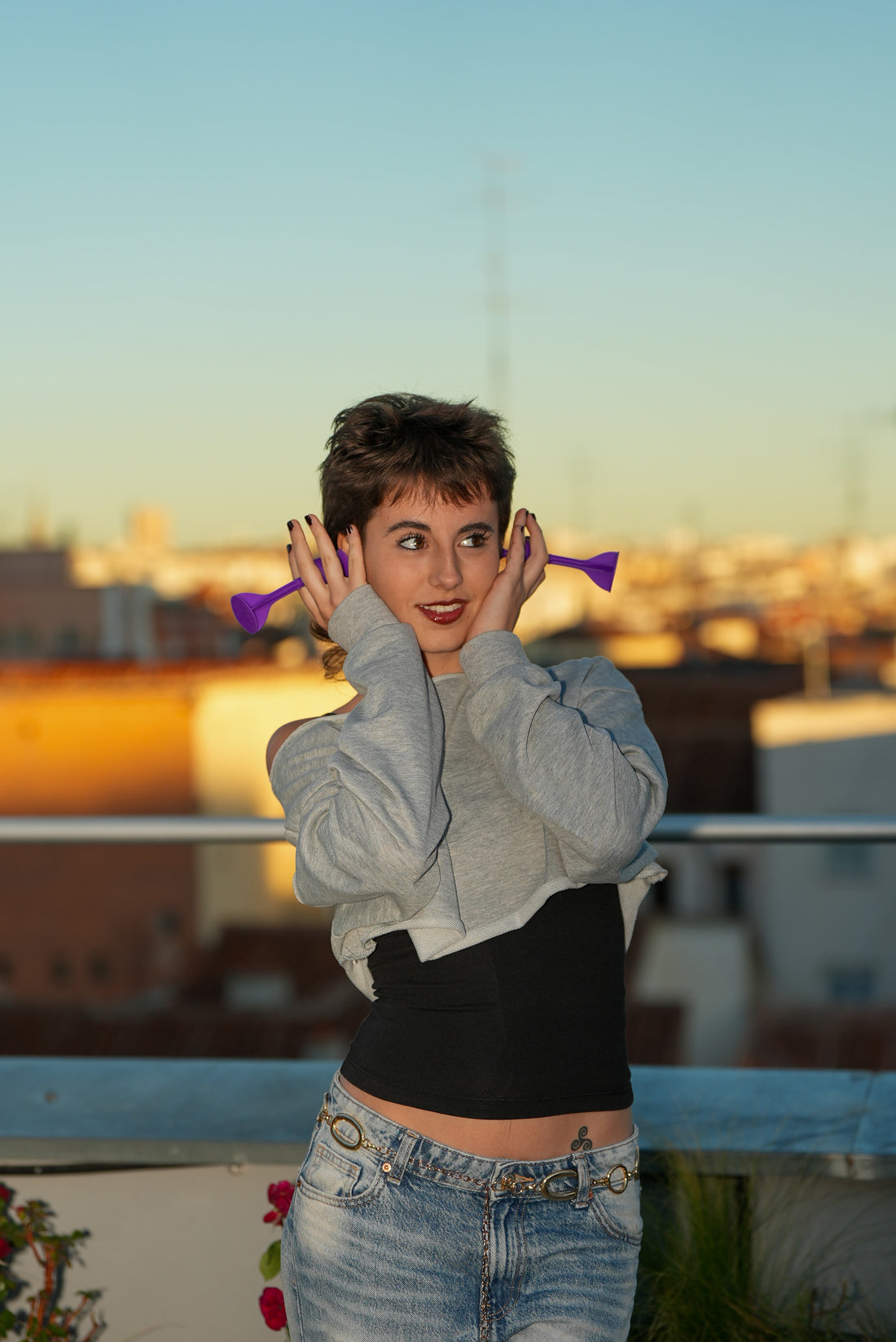 Two friends on a Madrid rooftop at golden hour, holding red and yellow Tossit darts