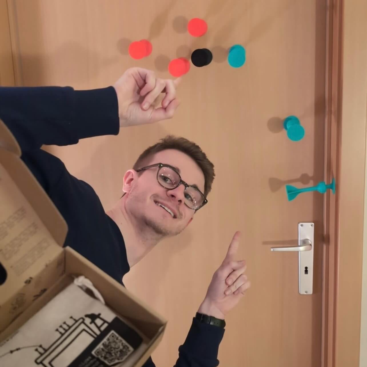 Person opening a box with colorful dots on a door